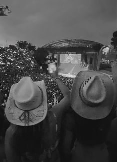 two people wearing hats are watching a concert