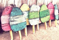 several wooden surfboards are lined up against a fence with pins sticking out of them