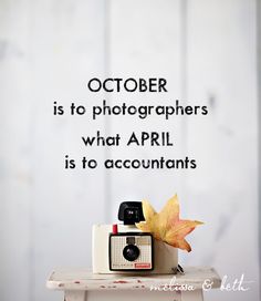 an old camera sitting on top of a table next to a fall leaf and the words october is to photographers what apri is to accountants