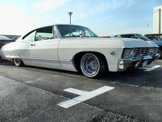 an old white car parked in a parking lot