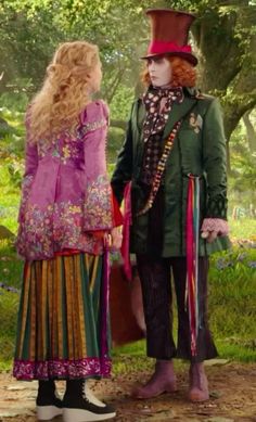 two people dressed in costumes standing next to each other on a dirt road with trees and grass behind them