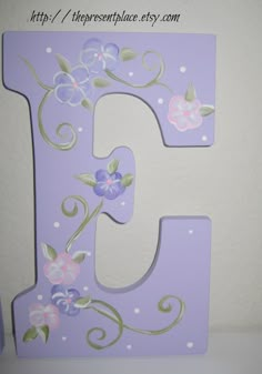 the letter e is decorated with flowers and leaves on it's side, along with a polka dot wall hanging