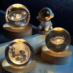 three glass globes sitting on top of wooden bases with an astronaut in the background