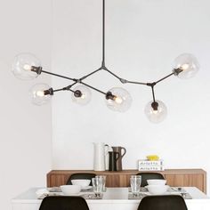 a dining room table and chairs with lights hanging from the ceiling