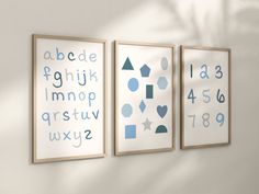 three framed art pieces on the wall with numbers and shapes in blue, grey and white