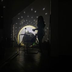 a woman standing next to a table in a dark room with lights shining on the walls