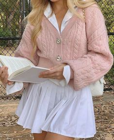 Blonde girl holding and reading a book in a cute outfit. She is wearing a pink cardigan over a white shirt and white tennis skirt. She has a bag over her shoulder. Cute outfit and cute pose. Light academia aesthetic Looks Pinterest, Preppy Outfit, Pinterest Outfits, White Skirt, Pink Outfits, Pink Outfit