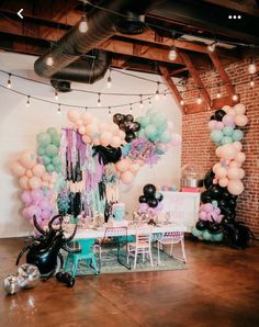 balloons and streamers are hanging from the ceiling in front of a table with chairs