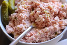 a bowl filled with tuna and pickles on top of a table next to a fork