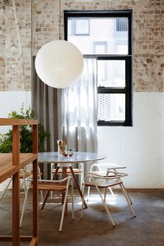 a table and chairs are in front of a window with a lamp hanging over it