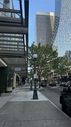 a city street with tall buildings and cars parked on the side walk next to it