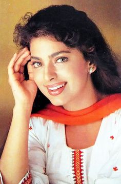 a woman wearing an orange scarf and white shirt smiling with her hand on her head