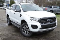 a white truck parked in a parking lot next to other cars and trucks behind it