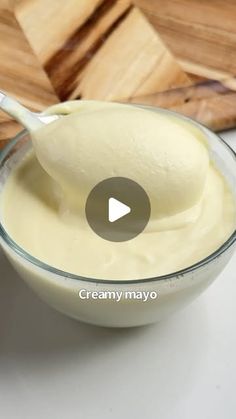 a bowl filled with cream sitting on top of a wooden cutting board