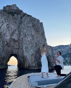 a man and woman standing on the deck of a boat in front of an arch