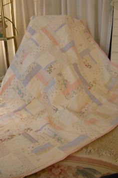 a bed with a quilt on top of it next to a lamp and window sill