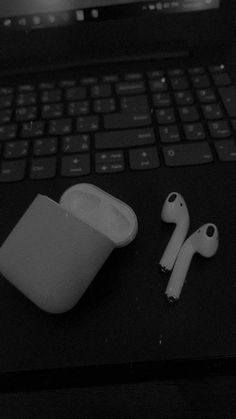 an apple airpods sitting on top of a laptop computer next to it's keyboard