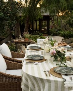 an outdoor dining table set with plates and place settings