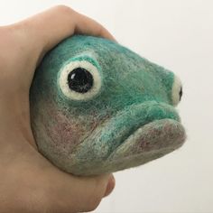 a close up of a person holding a small stuffed animal with one eye on it's face