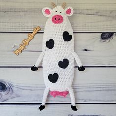 a crocheted cow ornament hanging from a hook on a wooden wall