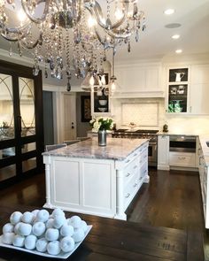 a white kitchen with an island and chandelier