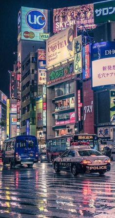 a city street filled with lots of traffic and tall buildings covered in neon signs at night