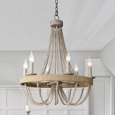 a chandelier hanging from the ceiling in a white room with candles on it