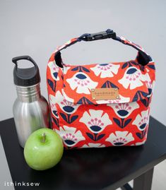 an apple, water bottle and lunch bag on a table