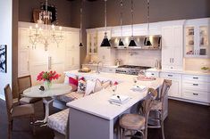 a kitchen with white cabinets and an island in the middle, surrounded by chandeliers