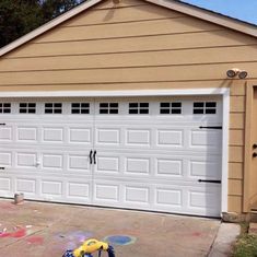 a yellow toy car parked in front of a garage door with graffiti on the ground