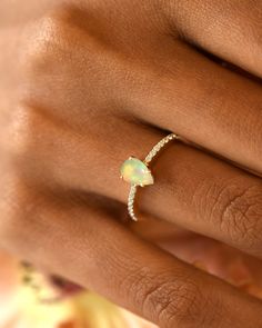 a woman's hand with a yellow opal and diamond ring on her finger