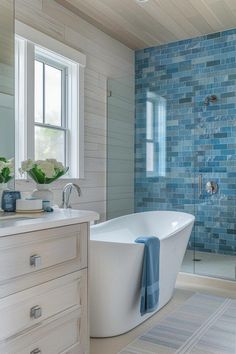 a white bath tub sitting under a bathroom window next to a walk in shower stall