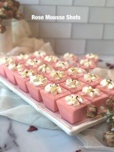 there are many small desserts on the table with flowers in the vase behind them