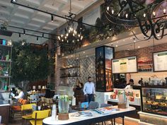 people sitting at tables in a restaurant with lots of lights hanging from the ceiling and plants growing on the walls