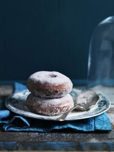 two donuts sitting on top of a plate next to a glass jar filled with liquid