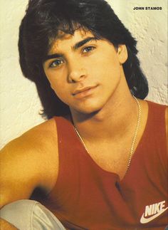 a young man with long hair wearing a red shirt and white pants is posing for a magazine cover