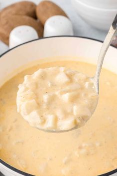 a spoon full of soup with some cookies in the background