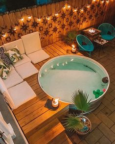 a hot tub sitting on top of a wooden deck next to a patio with lights