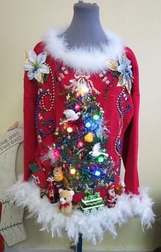 a red sweater decorated with christmas ornaments and lights on a mannequin's head