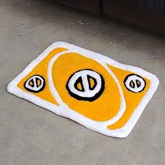 a yellow and white area rug with eyes on the floor next to a black couch