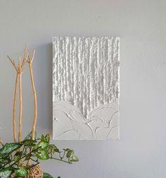 a white wall hanging next to a potted plant