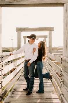 a man and woman standing on a wooden bridge together, with one holding the other's head