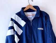 90’s ADIDAS streetwear sportswear windbreaker jacket size XLDESCRIPTION:Color: Navy Blue/WhiteStyle: Long Sleeve, Zip Front, Elastic Ribbed Cuffs & Bottom, Lined, 2 Slip Pockets, Rollaway HoodMeasurements:Entire Garment Length: 30 inchesPit to Pit: 25 inchesSleeve: 24 inchesFabric: 100% NylonSize: LargeCONDITION:Good condition, some wearMinor markings & discoloring on sleeve, see photosTAG DETAILS:Made by AdidasMade in Taiwan Adidas Streetwear, White Windbreaker, Streetwear Sportswear, Blue And White Style, Adidas Shop, Windbreaker Jacket, Vintage Boutique, Taiwan, Navy And White