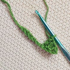 a crochet hook with a green thread on it