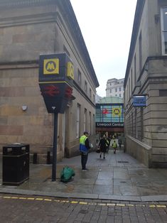 some people are walking down the street in front of some buildings with signs on them