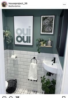 a bathroom with green walls and white tile flooring is pictured in this image, there are plants on the shelf above the sink