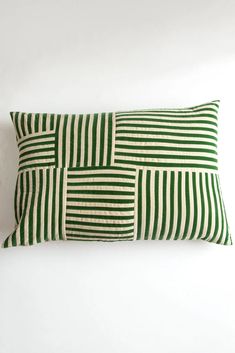 two green and white striped pillows sitting on top of each other in front of a white wall