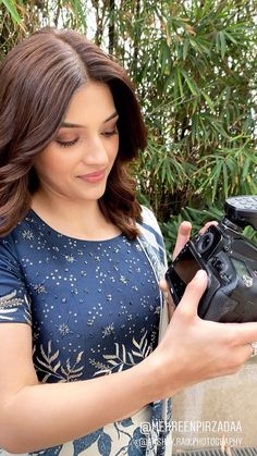 a woman holding a camera and looking at it