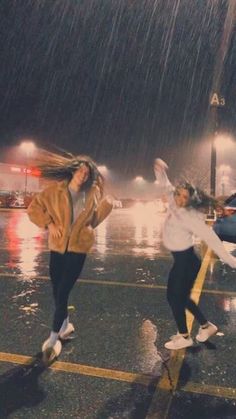 two girls jumping in the rain with umbrellas