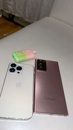 two cell phones sitting next to each other on a white table with a phone case